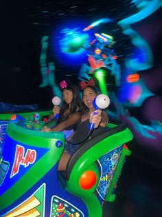 two girls are riding on a roller coaster at an amusement park in the night time