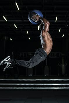 a shirtless man jumping in the air with a blue frisbee on his hand