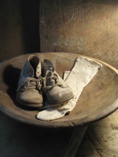 an old pair of shoes sitting on top of a wooden bowl next to a paper towel