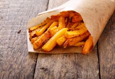 french fries in a wrapper on a wooden table