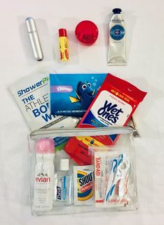 the contents of a travel bag laid out on a white tablecloth, including toothpaste, mouthwashes and dental floss