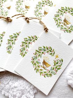 four christmas cards with holly wreaths and bells hanging from twine on white fabric