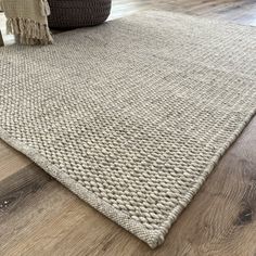 a rug on the floor with a basket next to it and a pillow in front of it