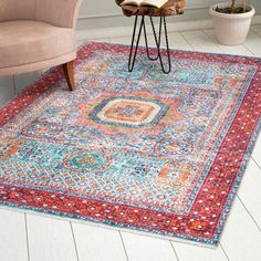 a colorful rug with an ornate design on the floor in front of a chair and potted plant