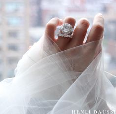 a woman's hand with a diamond ring on top of her wedding dress, in front of a window