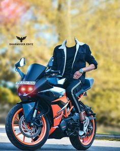 a man sitting on top of a motorcycle in front of some trees with orange rims