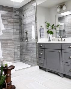 a bathroom with gray cabinets and white counter tops is pictured in this image, there are two plants on the side of the sink