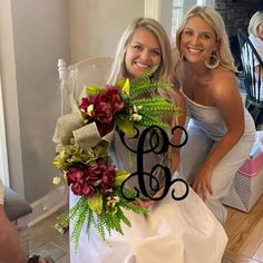 two beautiful women standing next to each other in front of a chair with flowers on it