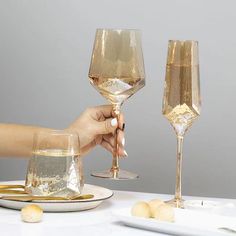 two champagne glasses being filled with liquid on a table