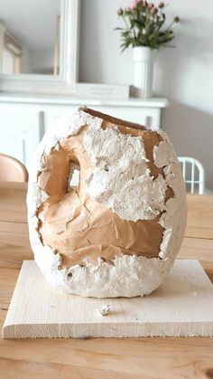 a large doughnut sitting on top of a wooden table next to a flower pot