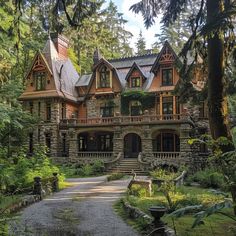 a large stone house surrounded by trees and greenery