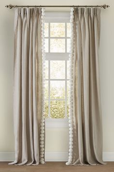 an open window with white curtains and pom - poms