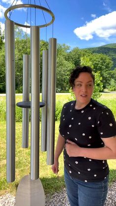 a woman standing next to a wind chime