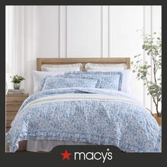 an image of a bed with blue and white comforter set on top of it