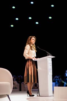 a woman standing at a podium in front of a crowd