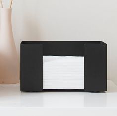 a black and white tissue dispenser next to a vase