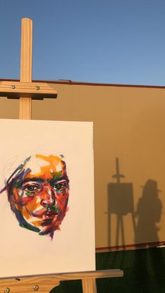 a painting is being displayed in front of a building with a cross on the side