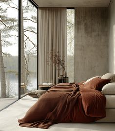 a bed sitting next to a window in a room with large windows and curtains on the wall