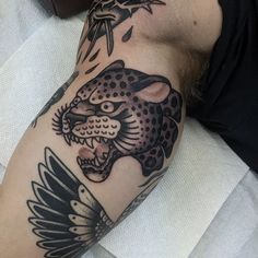 a man with a tattoo on his arm has a leopard and bird design on it