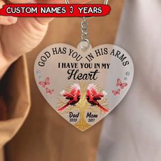 a person holding a heart shaped keychain that says, god has you in his arms i have you in my heart