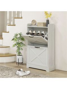 a white shoe rack with shoes on it and a potted plant next to it