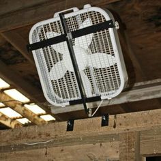 a white fan mounted to the side of a wooden ceiling in an unfinished building with exposed beams