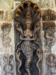 an intricately carved statue is displayed in front of a stone wall