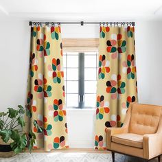 a living room with an orange chair and polka dot print curtains in front of a window