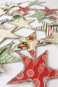 an assortment of christmas ornaments are arranged on a white tablecloth with red, green and silver stars