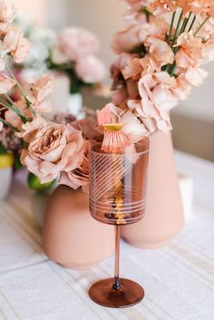 there is a vase with pink flowers in it and a candle holder on the table