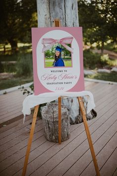 a pink and white sign sitting on top of a wooden easel