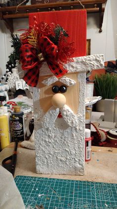 a wooden block with a santa clause head and red bow on it's head