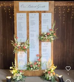 an arrangement of flowers and greenery is displayed on a wooden frame with seating cards