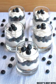 four glasses filled with dessert sitting on top of a table