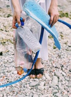 a person holding a water bottle and hose on the ground with rocks in front of them