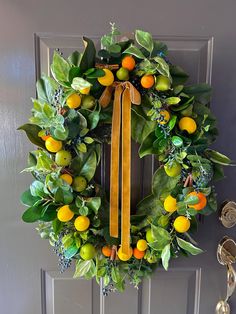 a wreath with oranges and green leaves hanging on a door