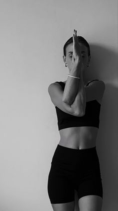 a black and white photo of a woman leaning against a wall with her hand on her face