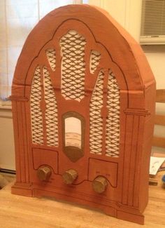 a wooden radio sitting on top of a table next to a window in a room