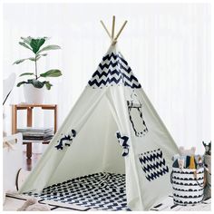 a teepee tent with blue and white designs on the front, sitting next to a potted plant