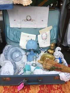 an open suitcase filled with various items on top of a table next to other things