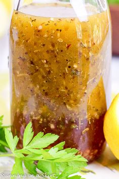 a jar filled with liquid sitting next to an apple and some green leafy leaves