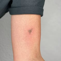 a woman's arm with a small bee tattoo on the back of her left arm