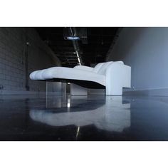 a white couch sitting on top of a shiny floor next to a brick wall in an empty room