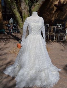 a white wedding dress on display in front of a tree