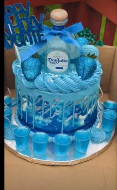 there is a blue cake with frosting on it and cups in front of it