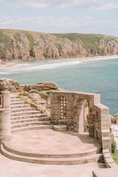 an outdoor area with steps leading to the ocean and cliffs in the background, along with blue water