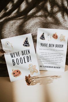 two greeting cards sitting on top of a bed next to an orange and black pumpkin