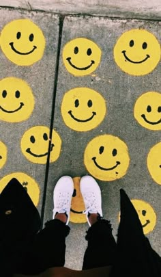 two people standing next to each other with smiley faces painted on the ground behind them