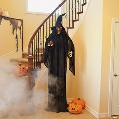 a man dressed as a ghost standing in front of a stair case with pumpkins