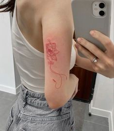 a woman with a flower tattoo on her arm taking a selfie in the mirror